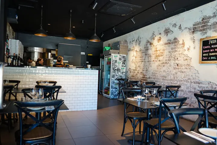 The Abbotsford dining room: bentwood chairs, brick wall and the white tiled pass