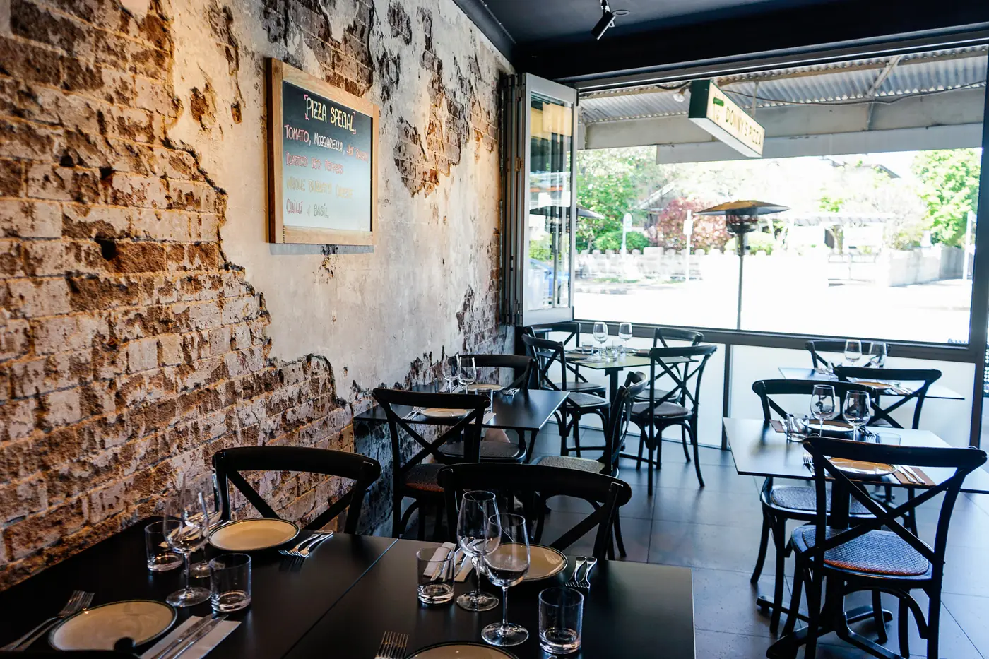 The Abbotsford dining room: brick wall, bentwood chairs and tables set with wine glasses