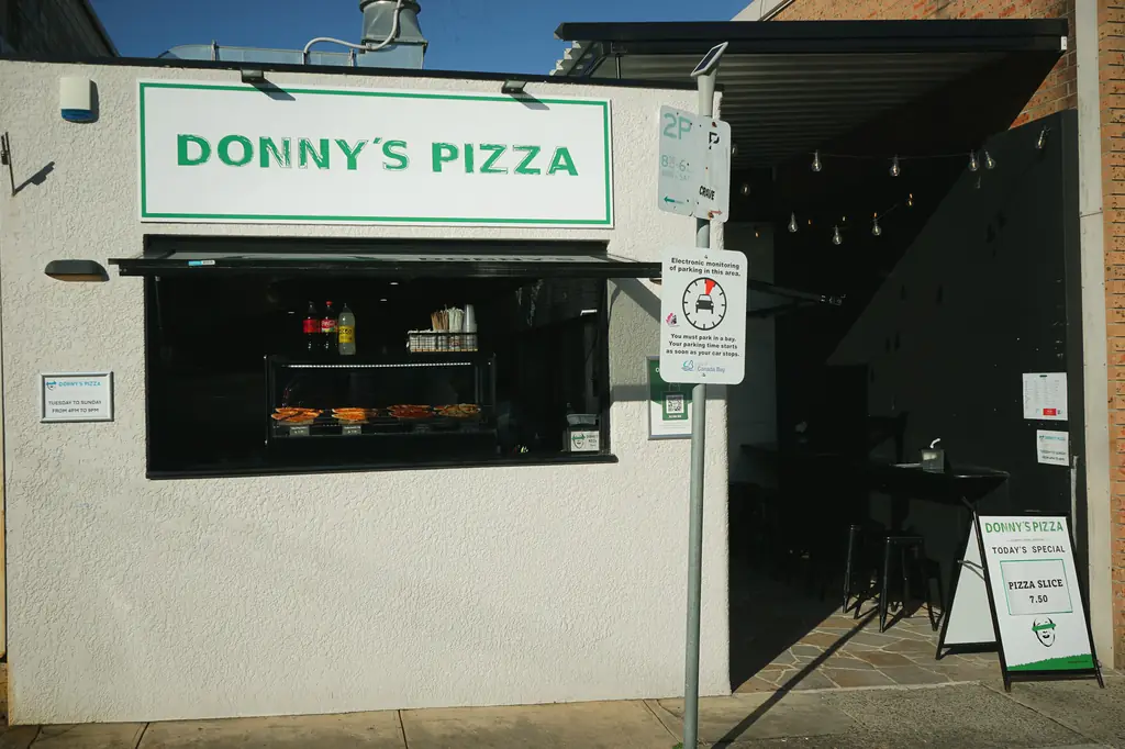 The Donny's Pizza shopfront in Drummoyne: white wall, green sign and the servery window