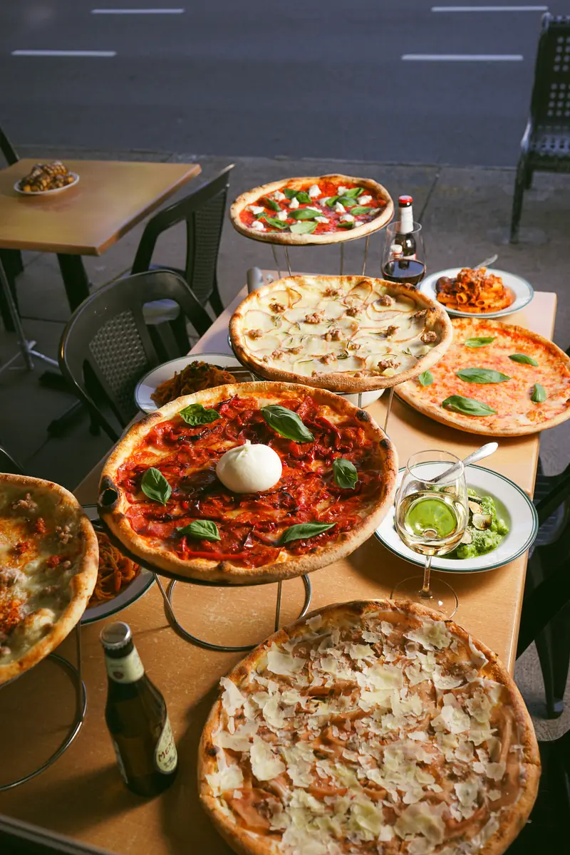 Pizzas on stands, pasta and white wine across a long table at Donny's Abbotsford